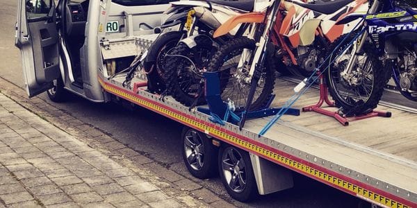 Meerdere KTM cross- en enduromotoren stevig vastgezet op het laadplatform met geblokkeerde voorwielen